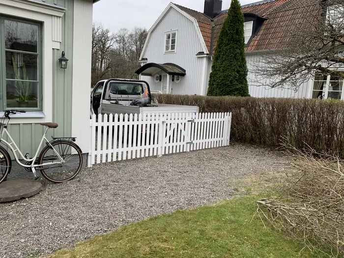 Vitt staket i trä mot grusgång