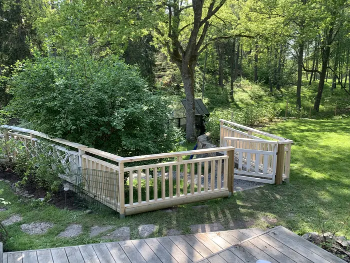 Terrasse avec garde-corps blanc, entourée de verdure