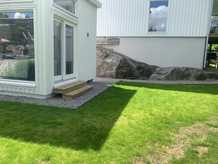 Nyanlagd gräsmatta vid vitt hus